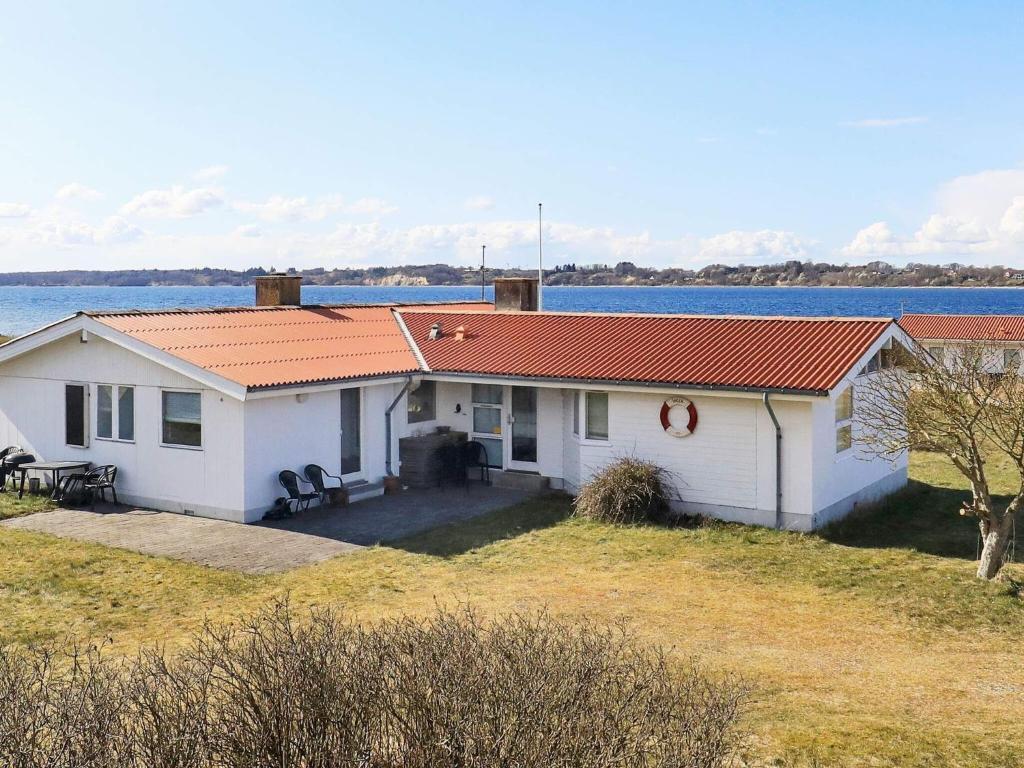 una casa blanca con techo naranja junto al agua en Holiday home Farsø XVIII, en Farsø