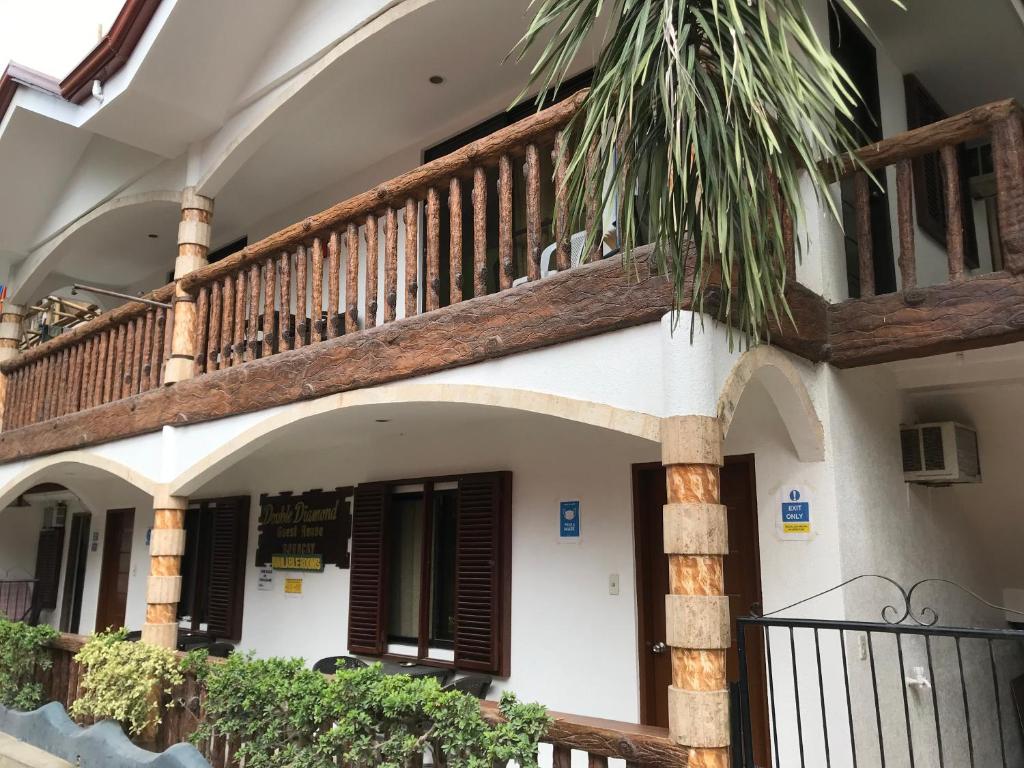a building with a balcony and a staircase at Double Diamond Inn Guest House in Boracay