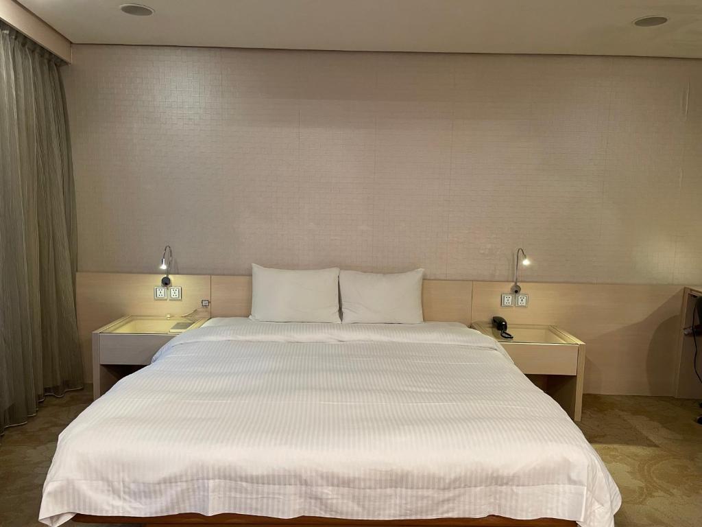 a large white bed in a room with two tables at Yomi Hotel - ShuangLian MRT in Taipei