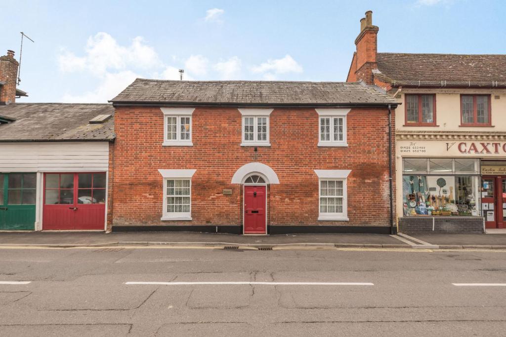 an old brick building with a red door on a street at Riverside House in Fordingbridge