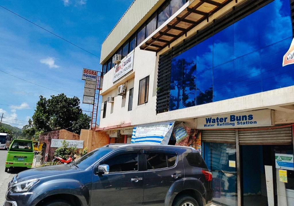 uma SUV azul estacionada em frente a um edifício em Segra Square Pension House em Balamban