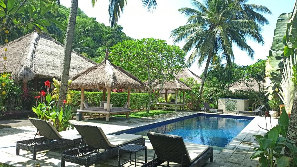 a resort with a swimming pool and chairs and a house at Mama Bella's Retreat in Senggigi 