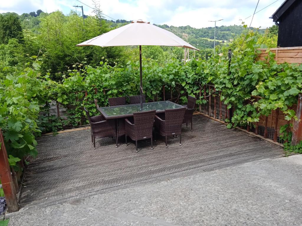 a patio with a table and chairs and an umbrella at Combe Cottage in Stroud