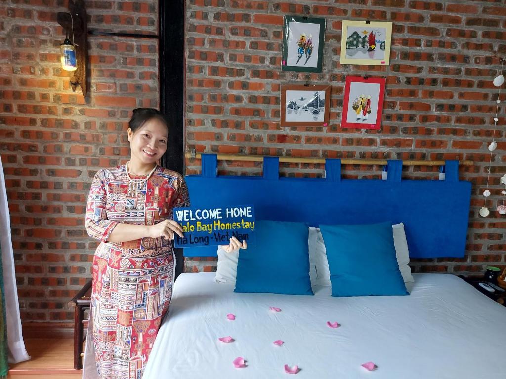 a woman is standing next to a bed at Halo Bay Homestay in Ha Long