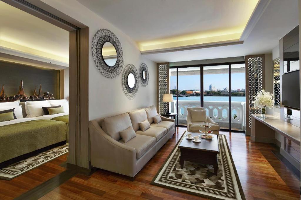 a bedroom with a bed and a couch and a table at Anantara Riverside Bangkok Resort in Bangkok