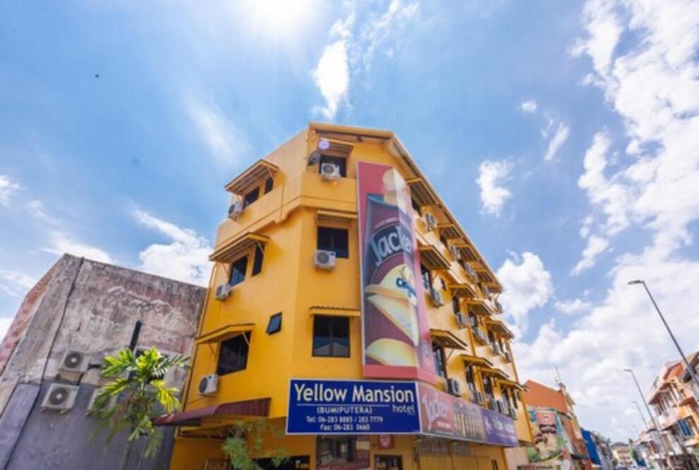un bâtiment jaune avec un panneau devant lui dans l'établissement Yellow Mansion Hotel, à Malacca
