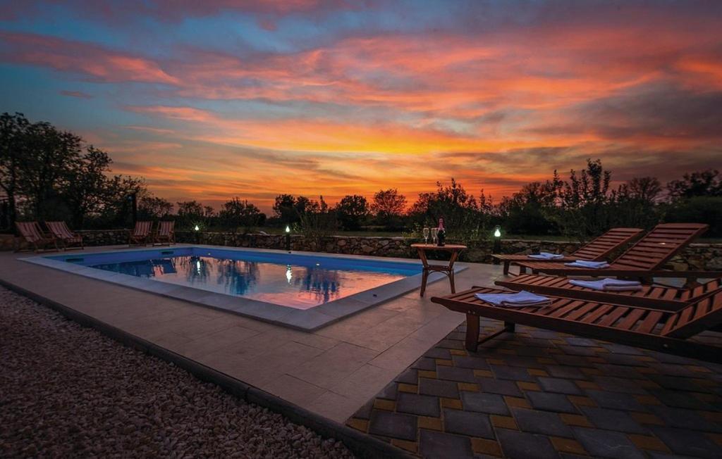 Holiday home Brist- with pool في Brištane: مسبح مع كرسيين للصاله وغروب الشمس