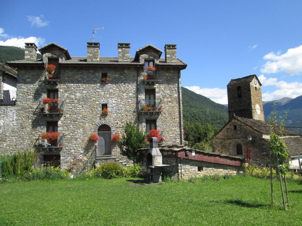 un antiguo edificio de piedra con flores en las ventanas en La Casita de Ordesa, en Frajén