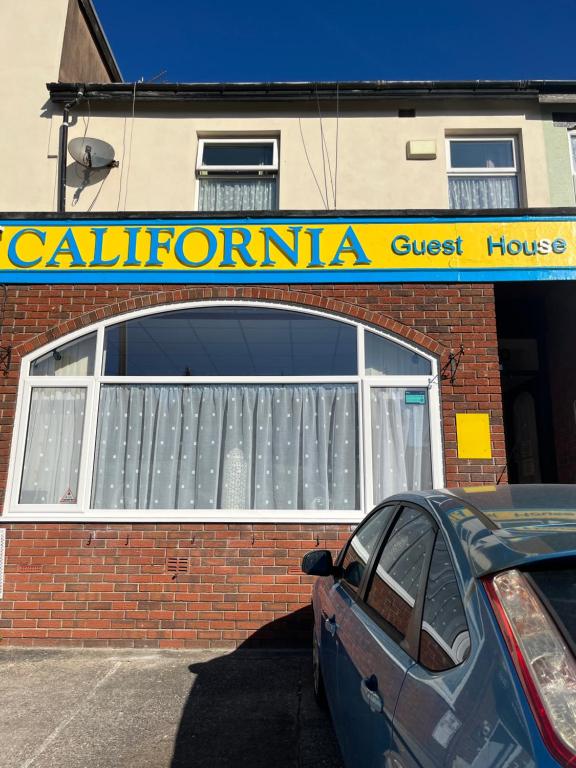 a car parked in a parking lot in front of a building at California Guest House in Blackpool
