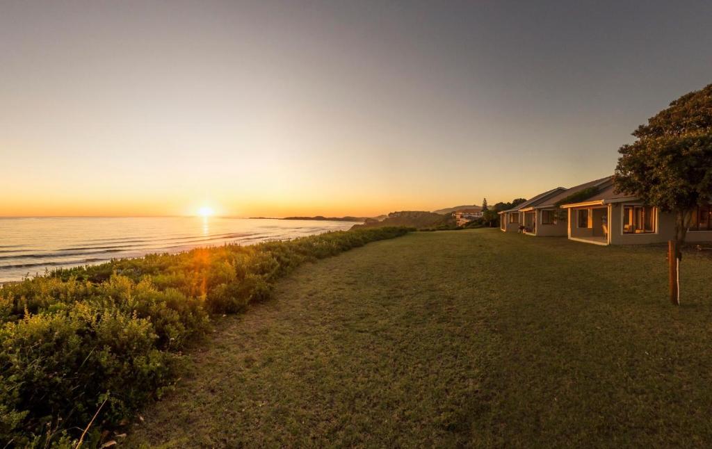 un tramonto sull'oceano con case sulla riva di Brenton Breakers a Brenton-on-Sea