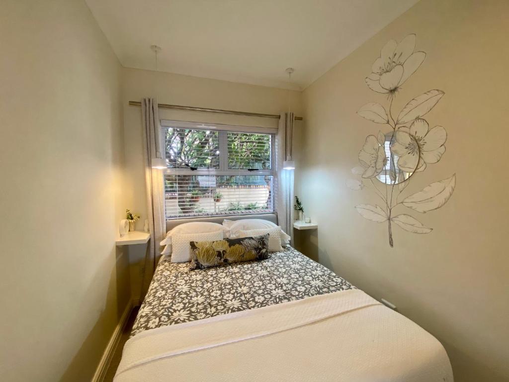 een kleine slaapkamer met een bed en een raam bij Walmer Cottage - Cute & Pet friendly in Kaapstad