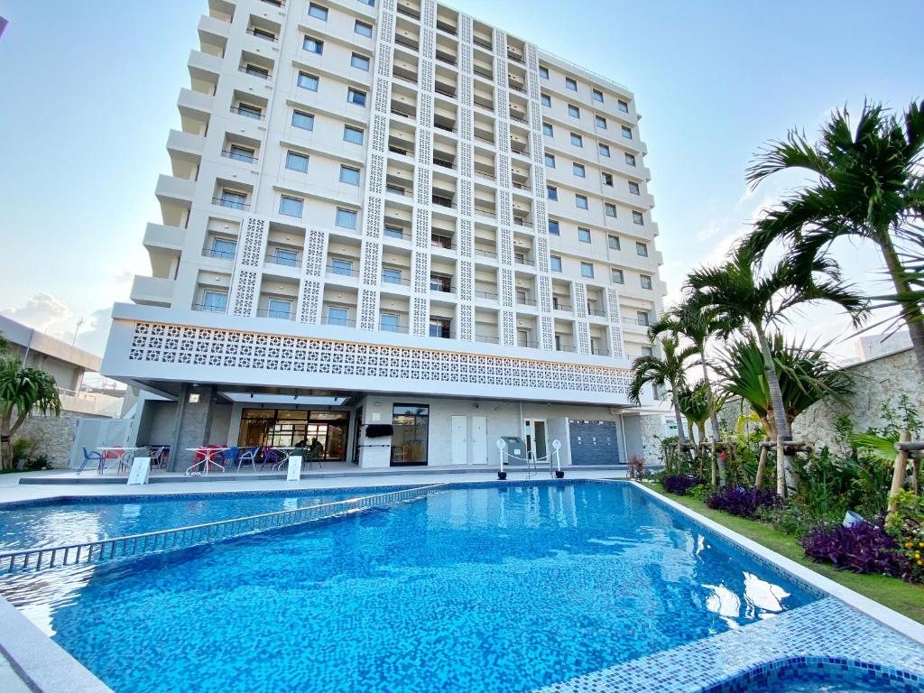 那覇市にある沖縄逸の彩ホテルの大きなスイミングプールが建物の前にあるホテル