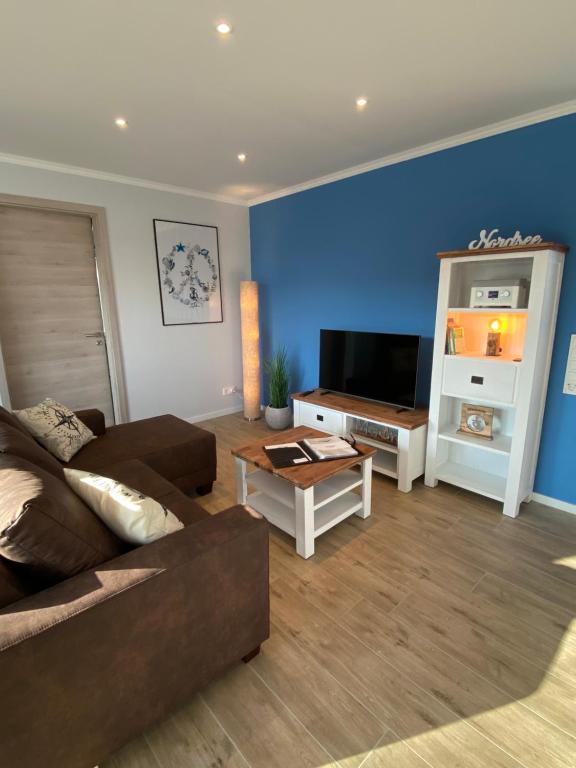 sala de estar con sofá y TV en Ferienwohnung Nordseenah, en Esens