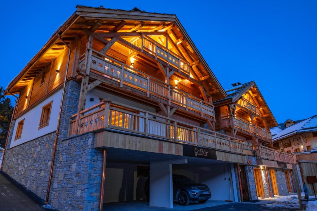 a large wooden house with a car parked in front of it at Chalet Galibier in Saint-Chaffrey