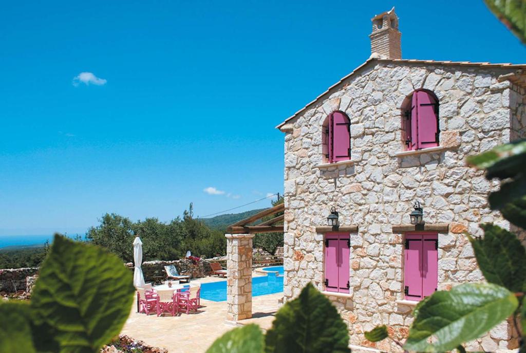 Agios LeonにあるAriadne Agios Leon Zakynthosのピンクの窓とプール付きの石造りの家