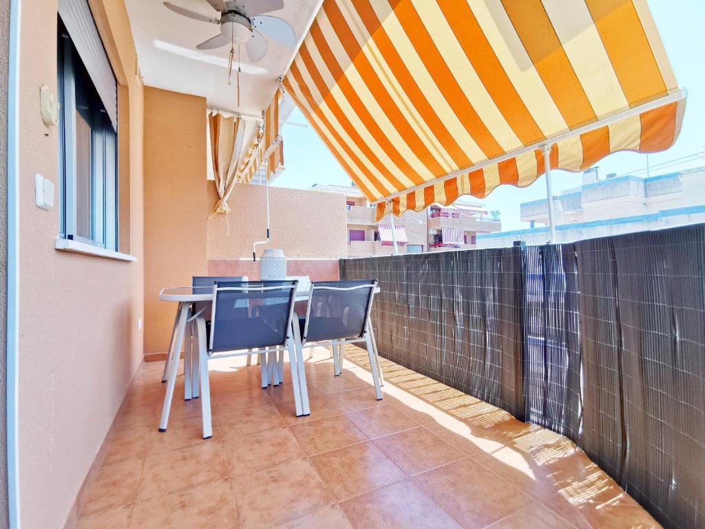 uma mesa e cadeiras numa varanda com um guarda-sol em Global Properties, Apartamento Ideal Familias en Canet Playa em Canet d'En Berenguer