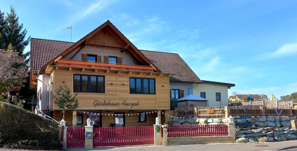 a large wooden house with a red fence at Gästehaus Auszeit in Unterlamm