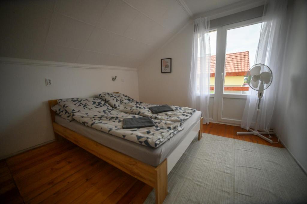 1 dormitorio con 1 cama, ventana y ventilador en Fortuna Vendégház, en Sárospatak