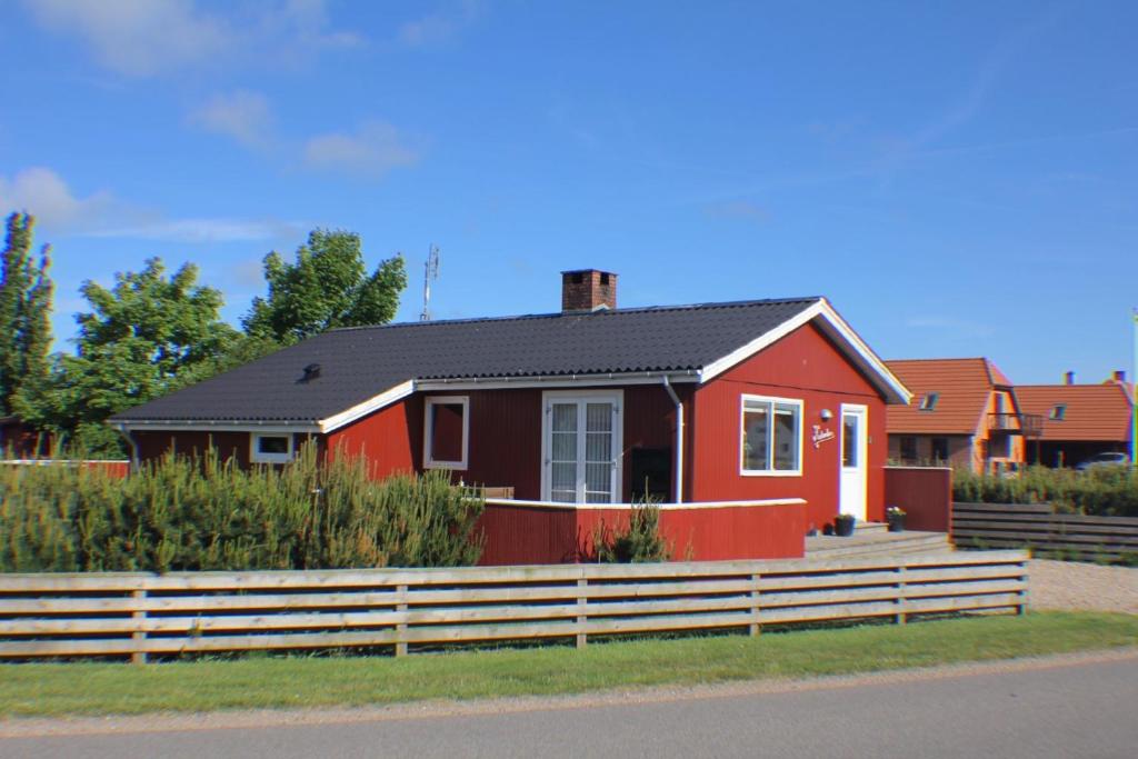 une maison rouge avec une clôture devant elle dans l'établissement The Little Red Cabin Near Blåvand!, à Blåvand