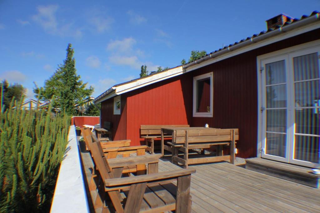 una terrazza con panche, tavolo e edificio di The Little Red Cabin Near Blåvand! a Blåvand