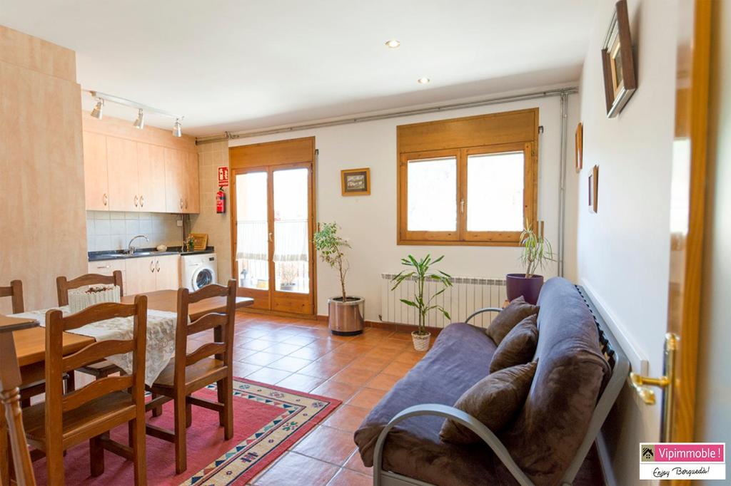 a living room with a couch and a table and a kitchen at Apartament Tritó - Rústico y acogedor con vistas - 2p in Guardiola de Berguedà
