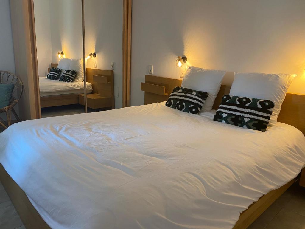 a large white bed with black pillows and a mirror at Résidence Les Sources in Saint-Rémy-de-Provence