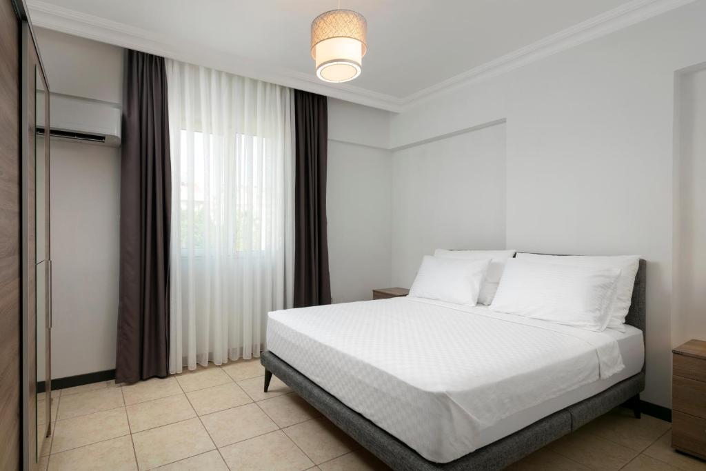 een slaapkamer met een wit bed en een raam bij Marvida Happy Suites in Antalya