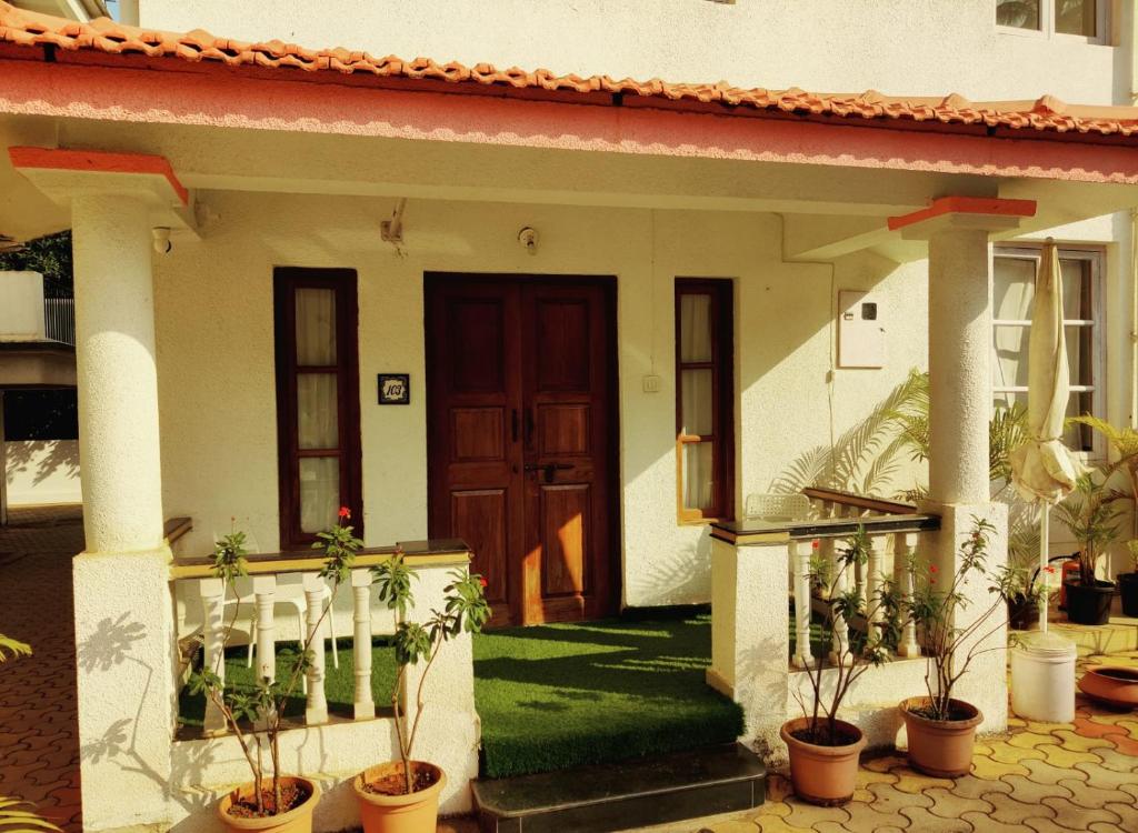 a house with potted plants in front of it at Perfect Stay Villa and apartment in Vagator