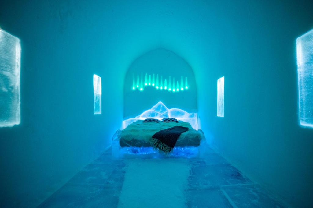 Habitación con cama en habitación con luces azules en Sorrisniva Igloo Hotel, en Alta