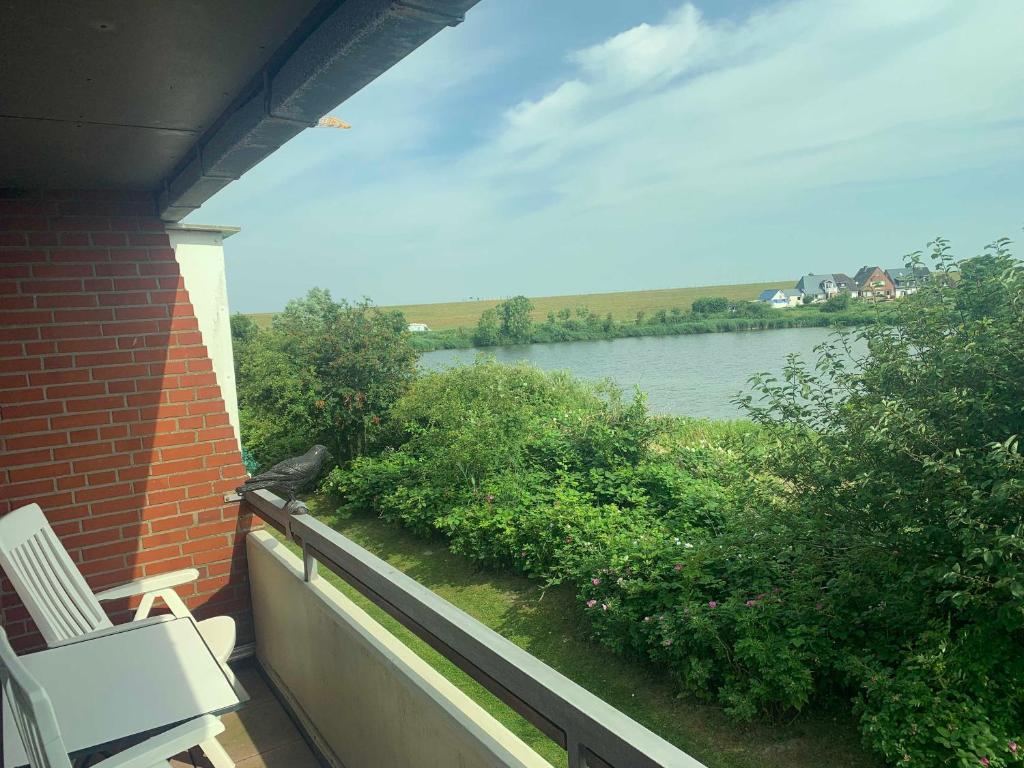 a balcony with a chair and a view of a river at Appartement 18 in Nordstrand