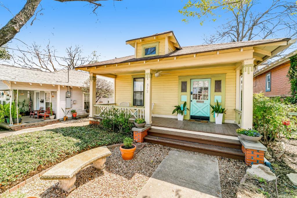 a yellow house with a bench in front of it at Beautiful Art Bungalow in Dallas