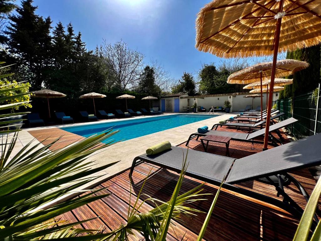 einen Pool mit Stühlen und Sonnenschirmen neben einem Pool in der Unterkunft Résidence Les Sources in Saint-Rémy-de-Provence