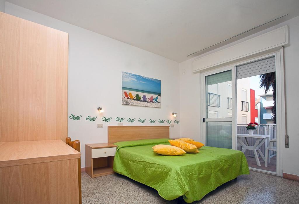 a bedroom with a green bed and a balcony at Hotel Amalfi & Dépendance in Lignano Sabbiadoro