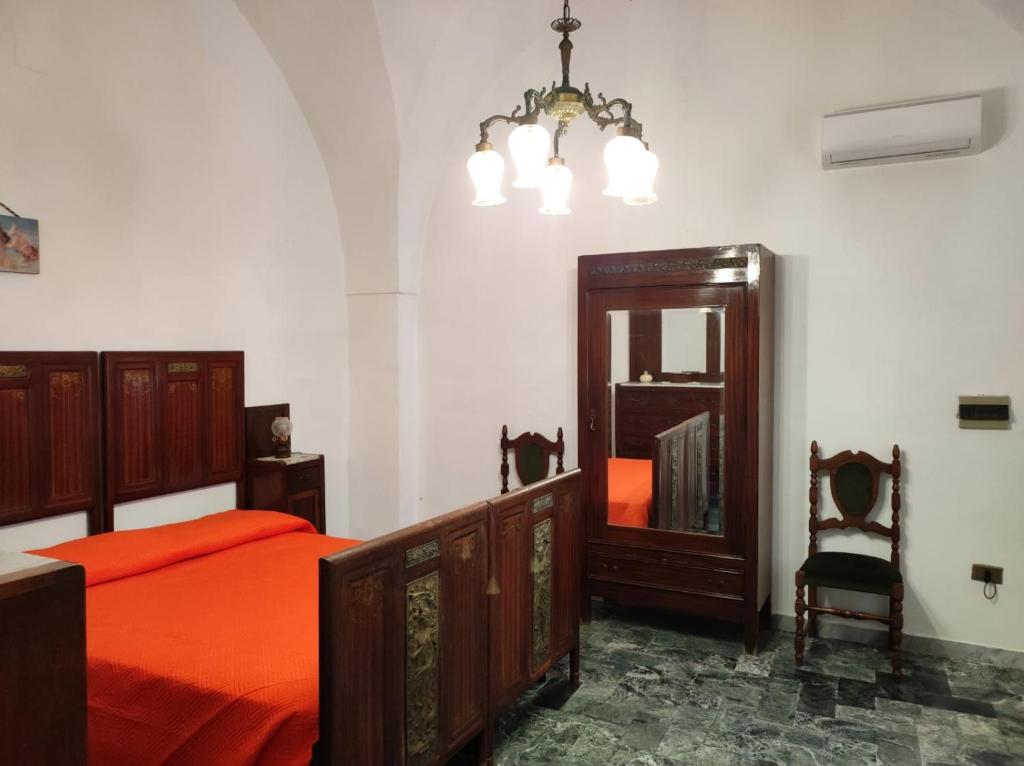 1 dormitorio con cama, espejo y silla en Dimora di nonna Nina, en Galatone