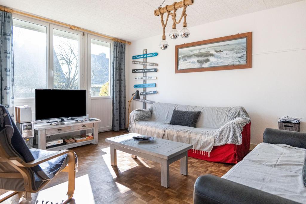 uma sala de estar com um sofá e uma televisão em Le Roulis em Saint-Cast-le-Guildo