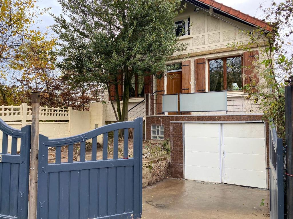 une clôture bleue devant une maison avec garage dans l'établissement Maison spacieuse à Saint-Brice-sous-Forêt avec jardin 90 m², à Saint-Brice-sous-Forêt