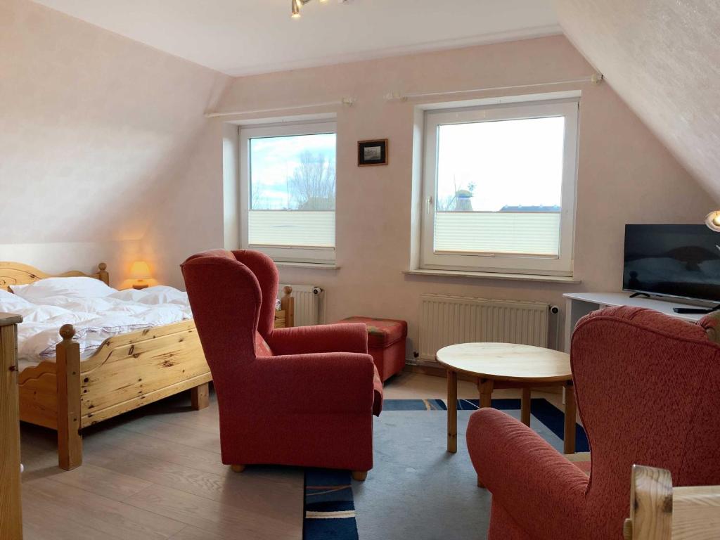 a bedroom with a bed and two chairs and a table at Appartement Möhlkiek in Nordstrand