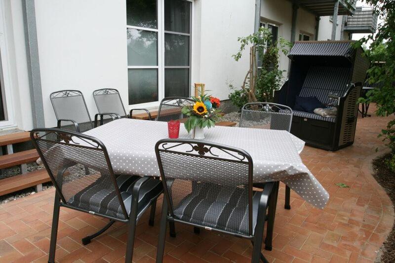 a table and chairs with a table and flowers on a patio at Landhaus Immenbarg, Auszeit in Warnemünde