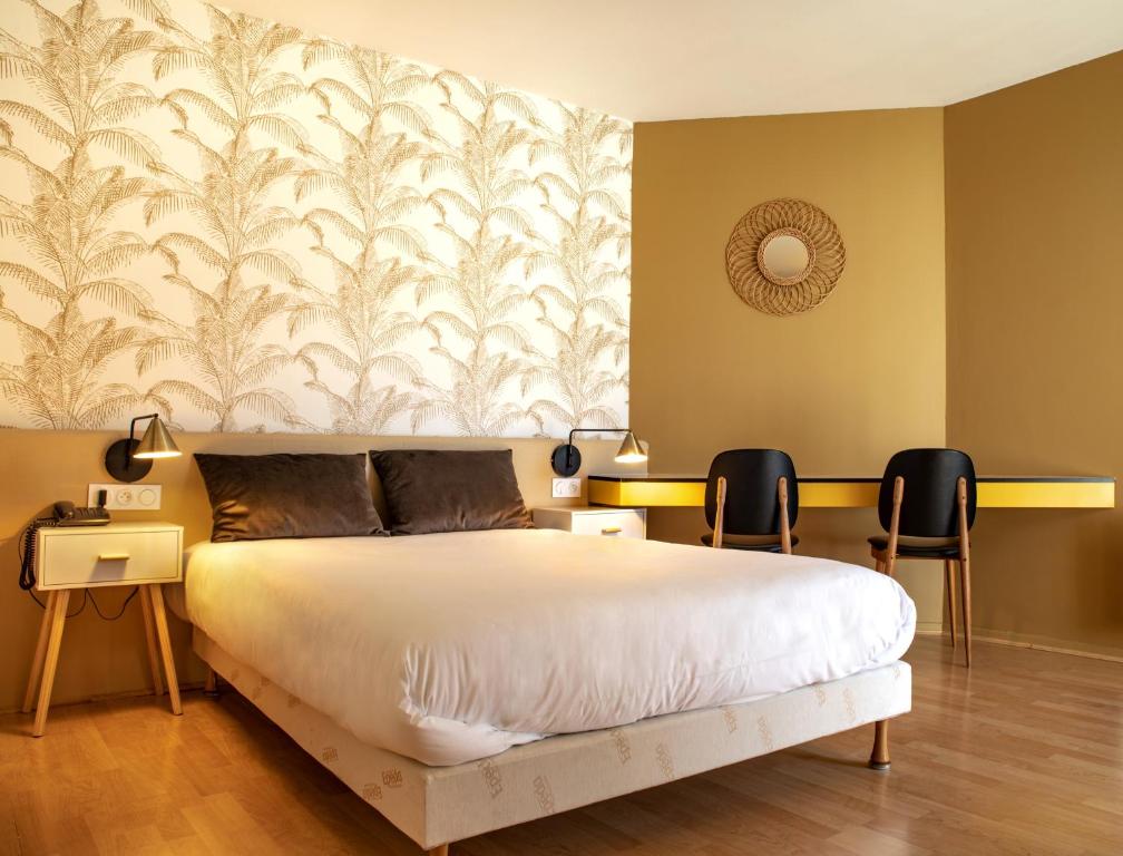 a bedroom with a large white bed and two chairs at Grand Hôtel du Parc in Florac