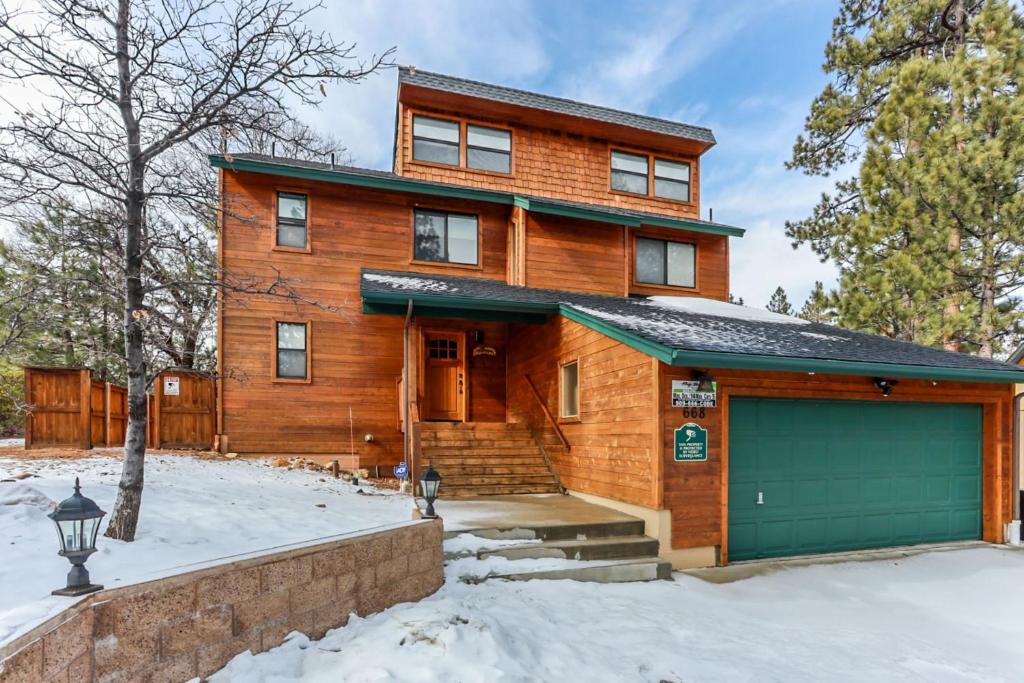 a wooden house with a garage in the snow at Luxury Lodge-1888 by Big Bear Vacations in Big Bear Lake