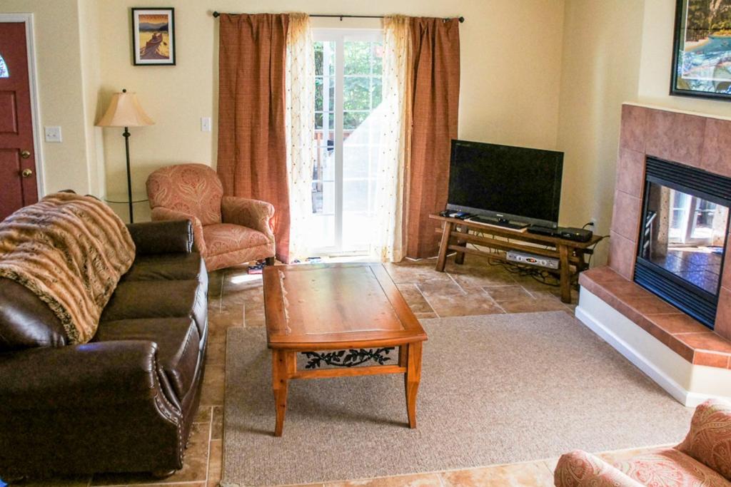 a living room with a couch and a tv at Willard Lake House in Bass Lake