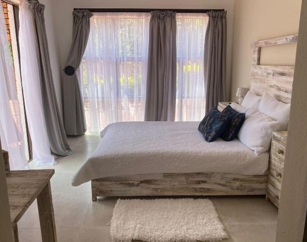 um quarto com uma cama e uma grande janela em Lime Court two em Pretoria
