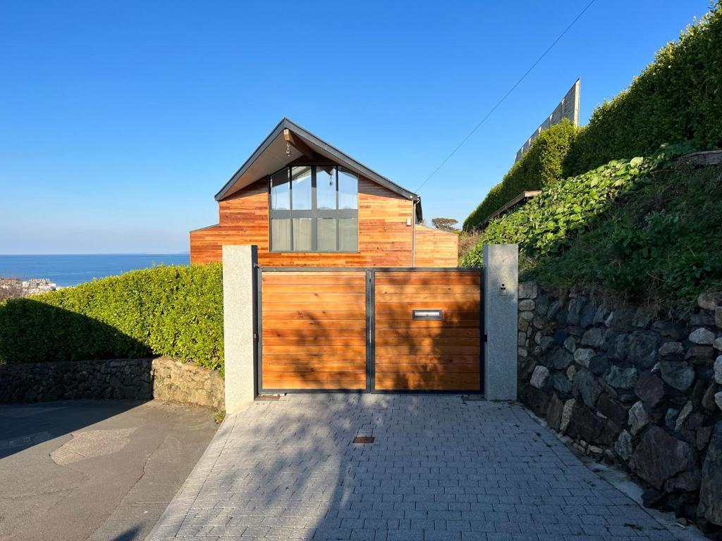 a house with a wooden garage with a stone wall at Uno - St Ives in St Ives