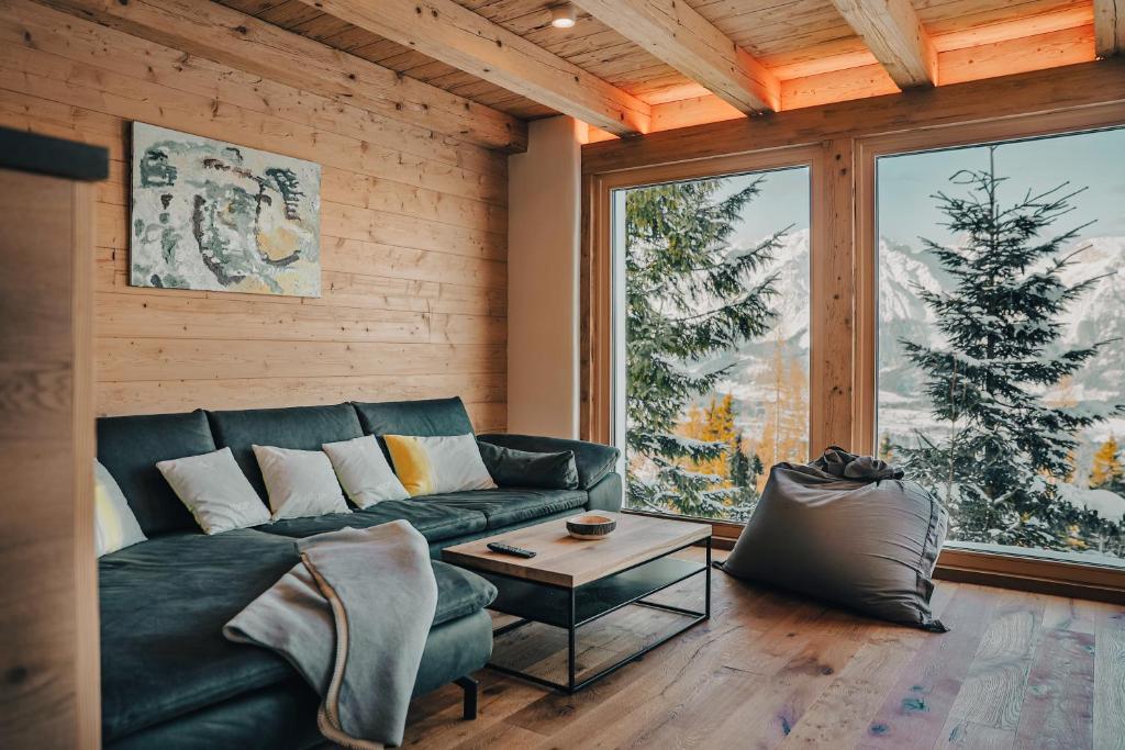 a living room with a green couch and a large window at Planai Apartment mit Dachstein Blick in Schladming