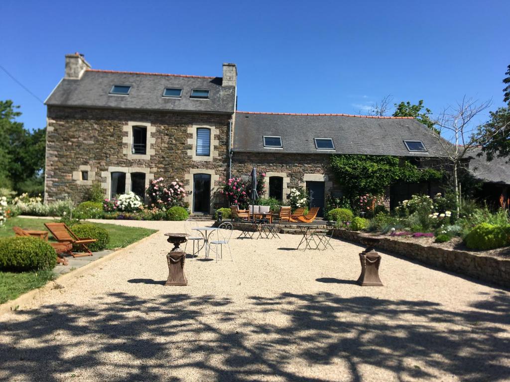 een groot stenen huis met tafels en stoelen in een tuin bij Demeure du Porzou, chambres d'hôtes de charme dans demeure d'exception, parc paysager, spa, massages, proche Paimpol, classé 4 épis in Yvias