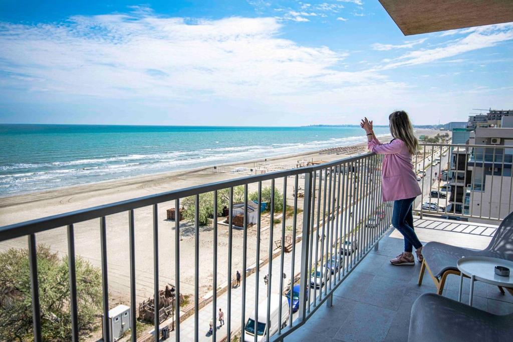 Eine Frau steht auf einem Balkon mit Blick auf den Strand in der Unterkunft Lemon Cliff Luxury B&B in Mamaia Nord – Năvodari