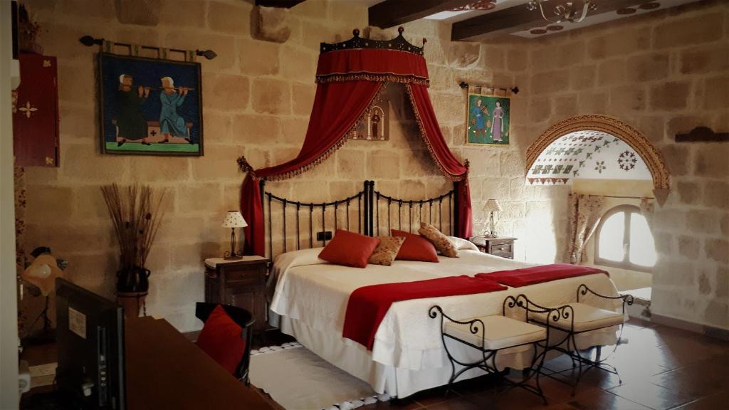 Schlafzimmer mit einem großen Bett mit rotem Baldachin in der Unterkunft Casa Rural Medieval Torre Fuerte S.XIII in Baños de Rioja