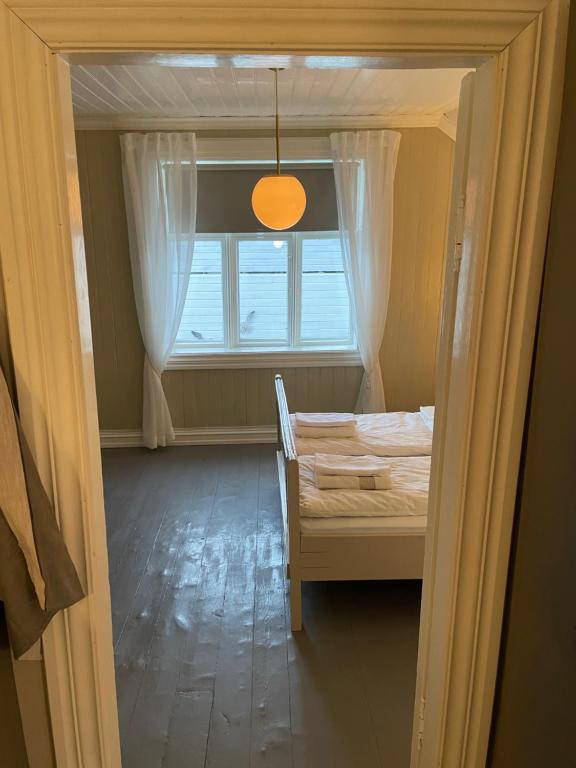 Cette chambre dispose d'une fenêtre, d'un lit et d'une chaise. dans l'établissement 2. etg i Dampskipsbrygga, Lødingen havn, à Lødingen