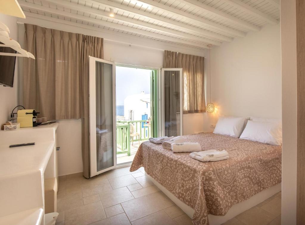 a bedroom with a bed and a large window at Mylos Suites in Mýkonos City