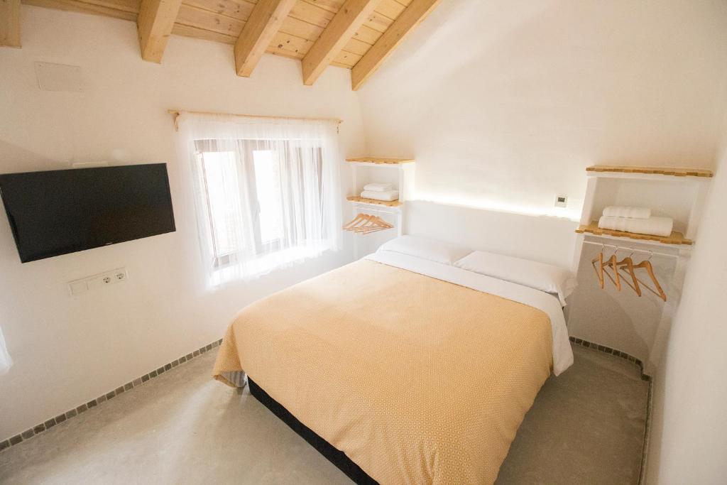 a white bedroom with a bed and a tv at El Pequeño Pajar in Majaelrayo